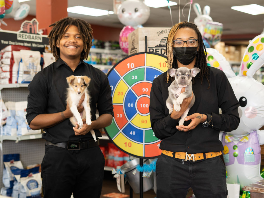 Two Petland employees holding cute puppies for sale while standing in a Petland Pembroke Pines store for the National Pet Day Carnival.