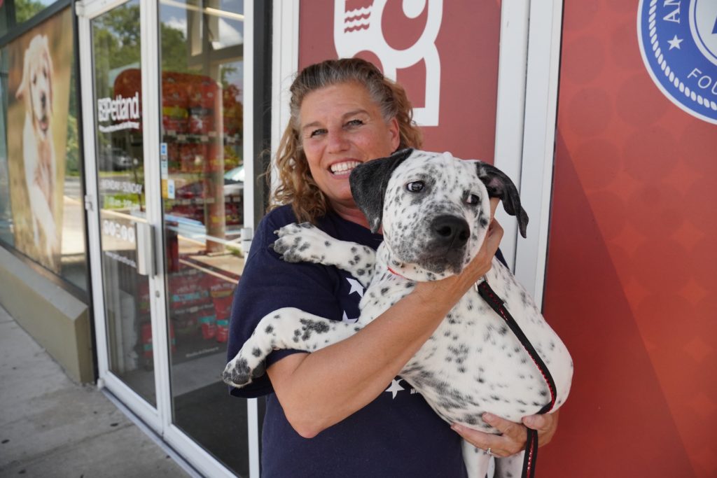 A cute puppy is held by a volunteer from Patriot Service Dogs.